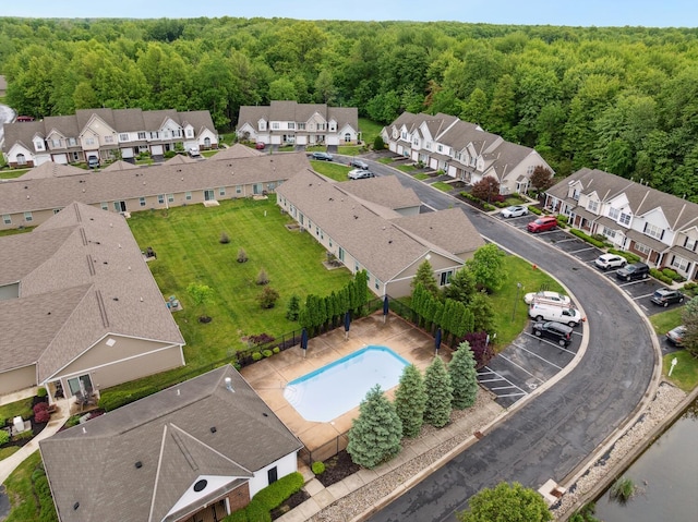 aerial perspective of suburban area featuring a heavily wooded area and a pool area