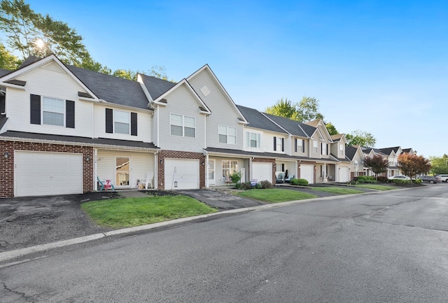 multi unit property featuring driveway, a garage, a residential view, brick siding, and a front yard