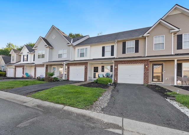 multi unit property with driveway, a garage, and brick siding