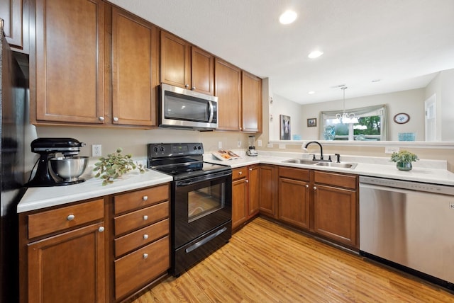 kitchen featuring appliances with stainless steel finishes, a sink, light wood finished floors, light countertops, and recessed lighting