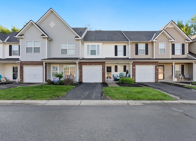 townhome / multi-family property with driveway, a garage, and brick siding