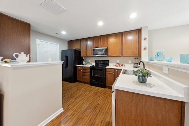 kitchen with black appliances, a sink, light wood-style flooring, light countertops, and recessed lighting