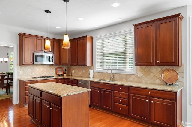 6415 Green Stone Loop, Dublin, OH 43016 - kitchen featuring stainless steel appliances, a sink, light wood finished floors, decorative light fixtures, and light stone counters