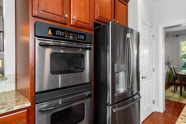 6415 Green Stone Loop, Dublin, OH 43016 - kitchen with appliances with stainless steel finishes, dark wood-style flooring, light stone counters, and brown cabinets