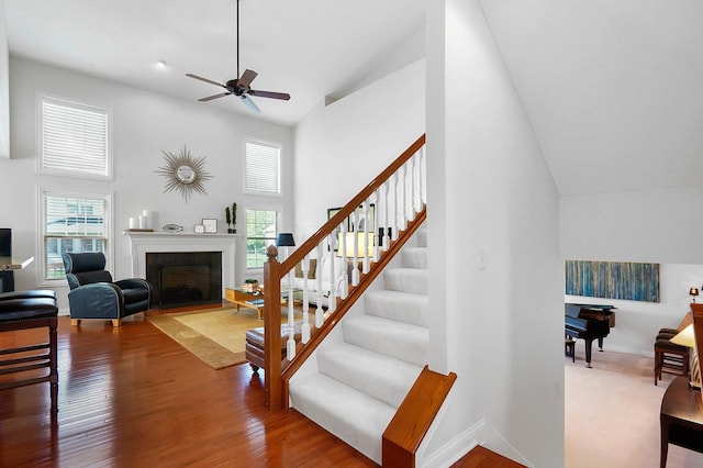 6415 Green Stone Loop, Dublin, OH 43016 - stairs with high vaulted ceiling, a fireplace, a ceiling fan, baseboards, and wood finished floors