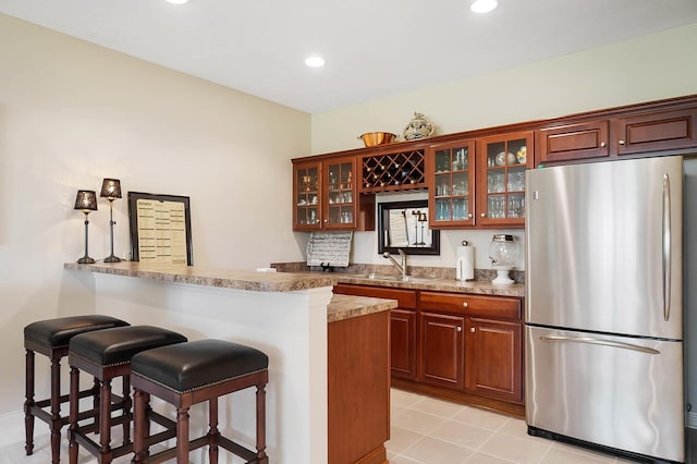 6415 Green Stone Loop, Dublin, OH 43016 - kitchen featuring freestanding refrigerator, a sink, a kitchen bar, a peninsula, and glass insert cabinets