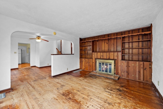 616 E Chestnut St, Mount Vernon, OH 43050 - unfurnished living room with a textured ceiling, a glass covered fireplace, wood finished floors, ceiling fan, and baseboards