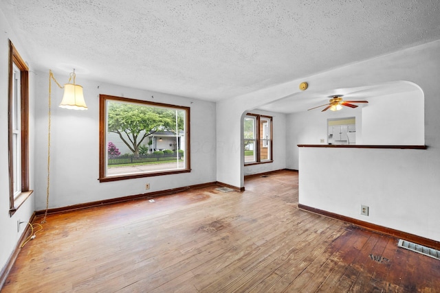 616 E Chestnut St, Mount Vernon, OH 43050 - unfurnished living room featuring a textured ceiling, hardwood / wood-style floors, baseboards, arched walkways, and a ceiling fan