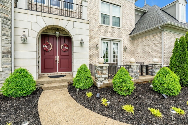 6540 Marshview Dr, Hilliard, OH 43026 - view of exterior entry featuring a shingled roof, a balcony, stone siding, and brick siding