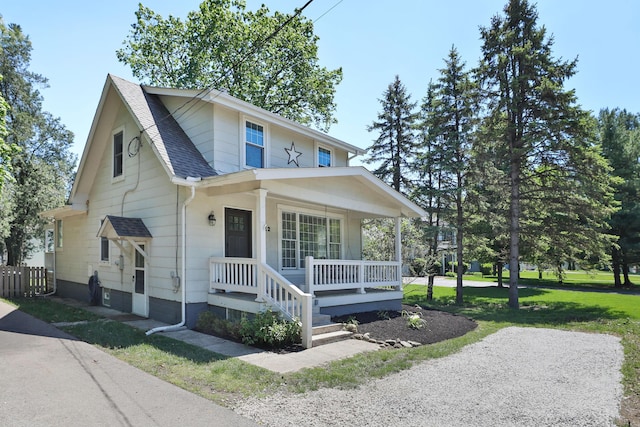 view of front of house with a porch, a shingled roof, and fence