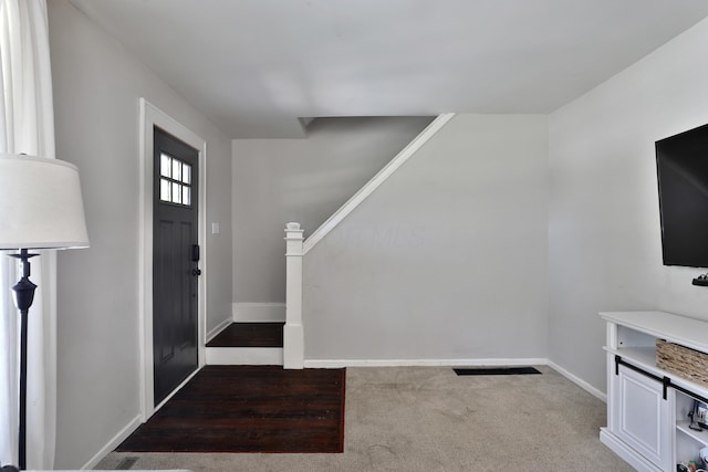 carpeted foyer with baseboards and stairs