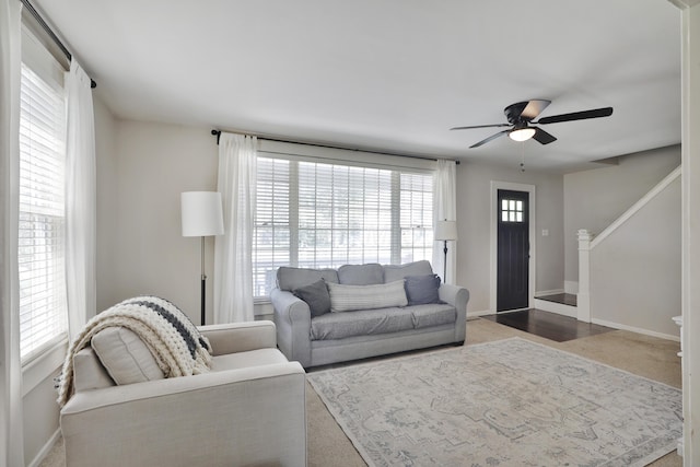 living room featuring ceiling fan, stairway, and baseboards