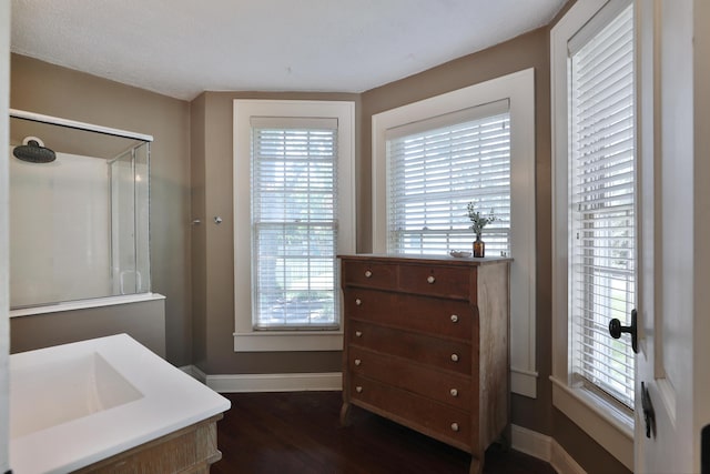 bathroom with baseboards, wood finished floors, and a shower with shower door