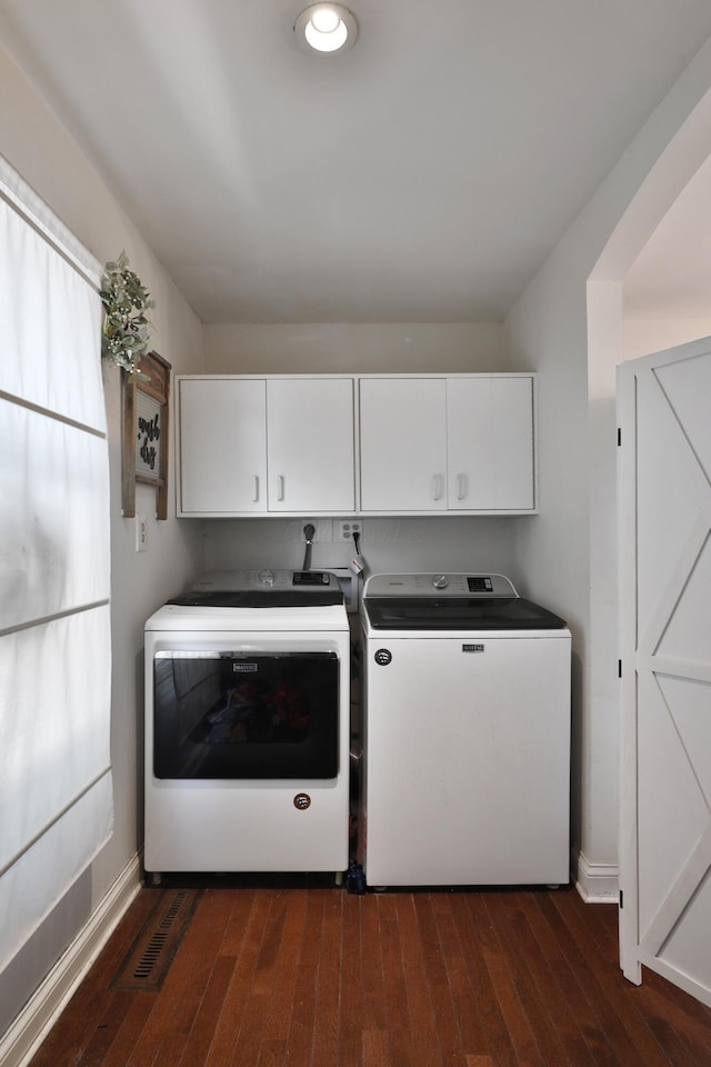 laundry room featuring washing machine and dryer, cabinet space, dark wood-style floors, and baseboards