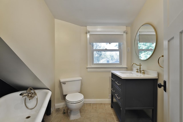 full bath featuring a freestanding tub, toilet, baseboards, and vanity
