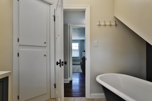 full bathroom featuring a soaking tub, baseboards, and vanity