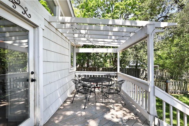 wooden terrace with outdoor dining space, fence, and a pergola