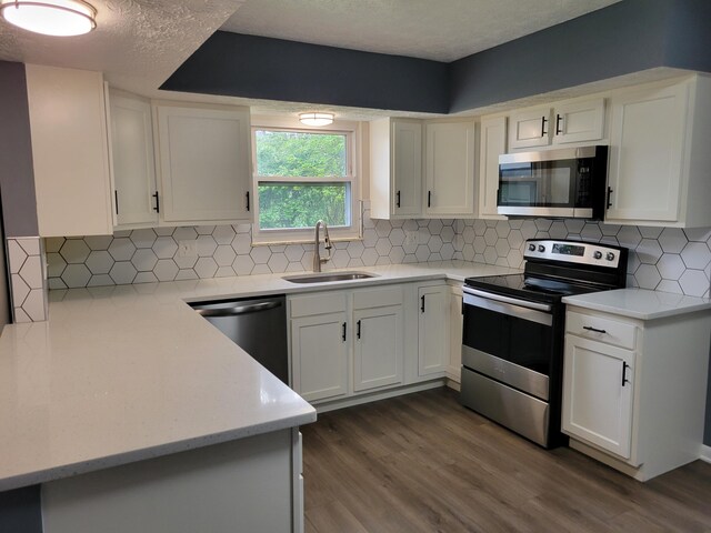 1989 Torchwood Dr, Columbus, OH 43229 - kitchen with stainless steel appliances, a sink, dark wood-style floors, white cabinets, and a textured ceiling