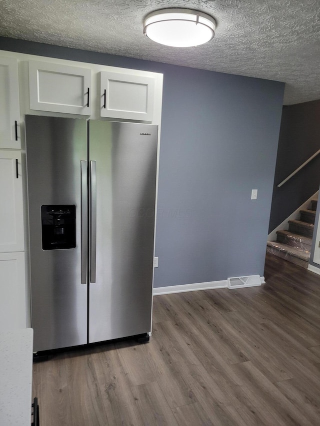 1989 Torchwood Dr, Columbus, OH 43229 - kitchen with stainless steel fridge with ice dispenser, white cabinetry, a textured ceiling, wood finished floors, and baseboards