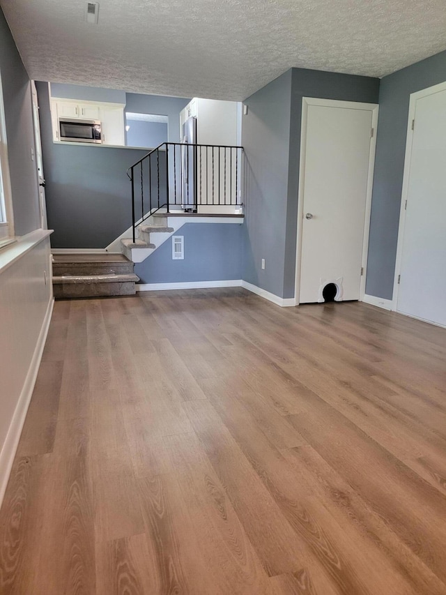 1989 Torchwood Dr, Columbus, OH 43229 - unfurnished living room featuring wood finished floors, stairway, baseboards, and a textured ceiling
