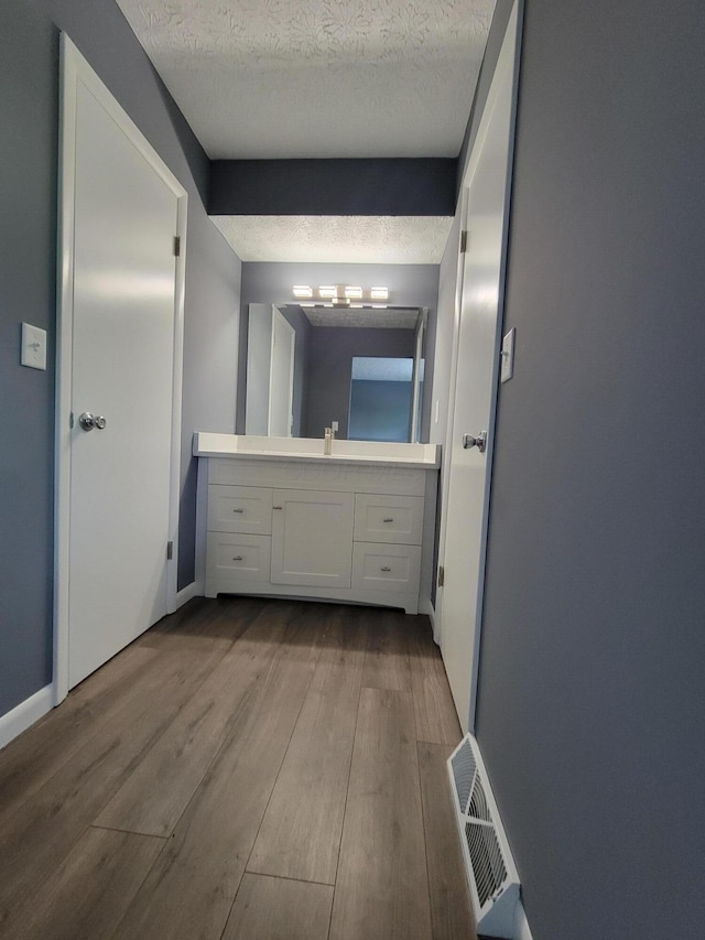 1989 Torchwood Dr, Columbus, OH 43229 - bathroom featuring wood finished floors, a textured ceiling, vanity, and baseboards