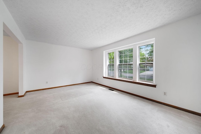 empty room featuring carpet, baseboards, and a textured ceiling