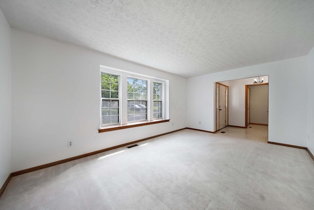 spare room featuring baseboards, carpet floors, a chandelier, and a textured ceiling