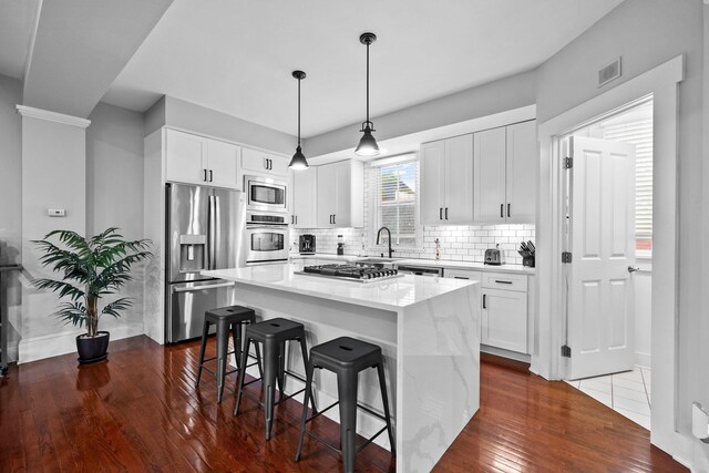 103 Lundy St, Columbus, OH 43215 - kitchen with stainless steel appliances, a sink, a breakfast bar area, dark wood finished floors, and white cabinetry