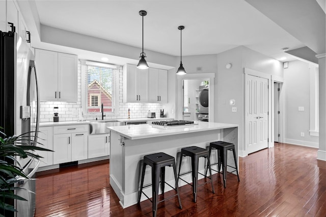 103 Lundy St, Columbus, OH 43215 - kitchen with stacked washer / drying machine, a sink, tasteful backsplash, stainless steel appliances, and a center island