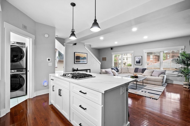 103 Lundy St, Columbus, OH 43215 - kitchen with stacked washer / drying machine, stainless steel gas stovetop, dark wood-type flooring, light stone counters, and a center island