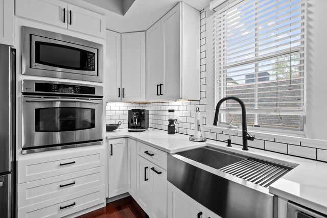 103 Lundy St, Columbus, OH 43215 - kitchen featuring appliances with stainless steel finishes, a sink, decorative backsplash, light stone countertops, and white cabinetry