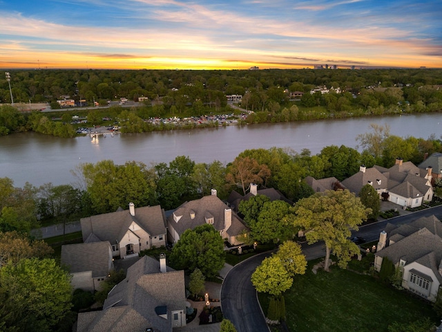aerial view at dusk of a water view, a residential view, and view of scattered trees