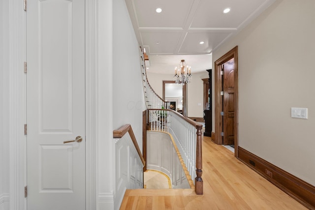 hallway with recessed lighting, a chandelier, light wood finished floors, an upstairs landing, and coffered ceiling