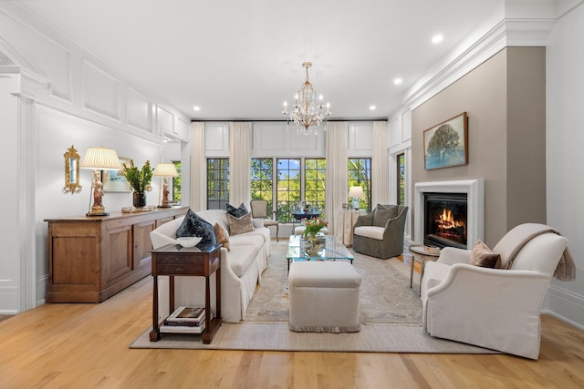 living area featuring light wood-style flooring, a glass covered fireplace, a chandelier, baseboards, and recessed lighting