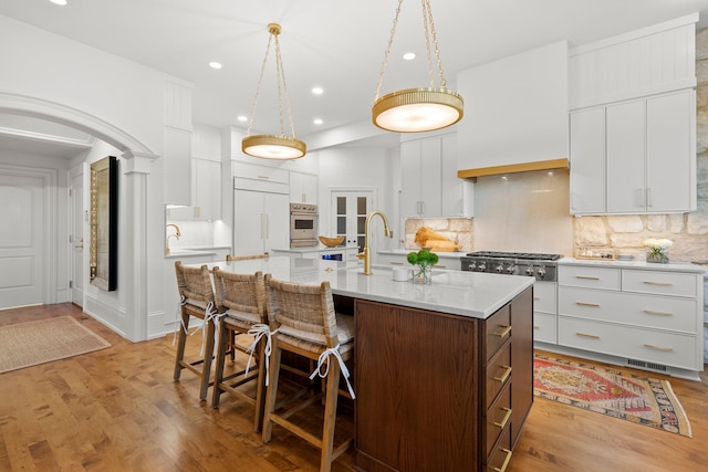 kitchen featuring a sink, light countertops, a breakfast bar area, tasteful backsplash, and recessed lighting