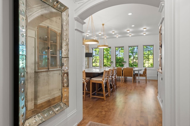dining room featuring wood finished floors, arched walkways, and recessed lighting