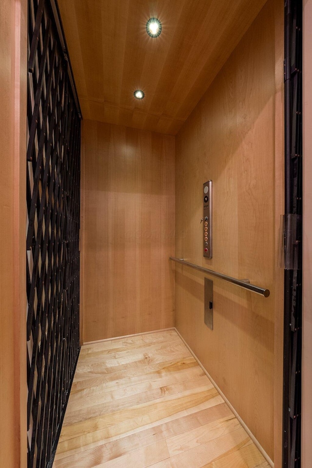 elevator featuring wood finished floors, wooden ceiling, recessed lighting, and wooden walls