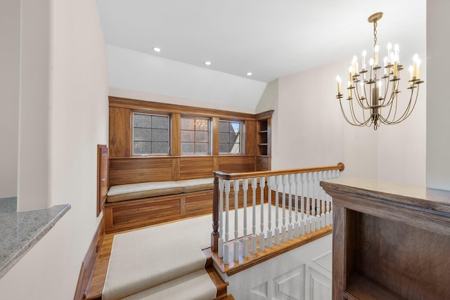 stairs with a chandelier, recessed lighting, wood finished floors, lofted ceiling, and baseboards