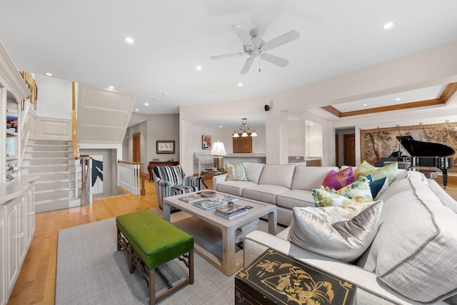 living area with light wood finished floors, recessed lighting, ceiling fan, ornamental molding, and stairs