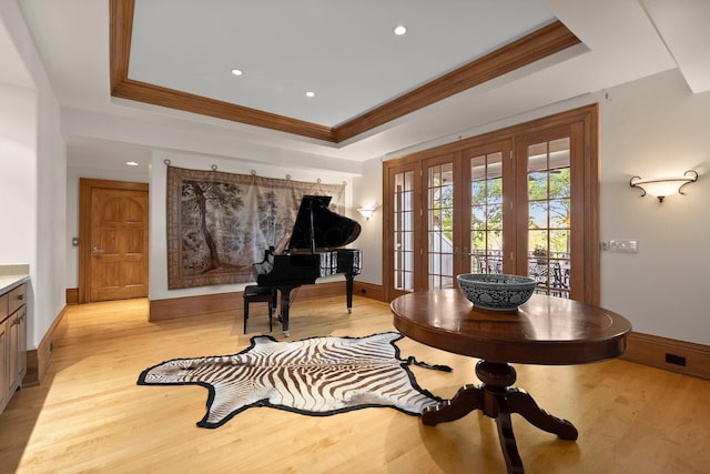 foyer entrance featuring a raised ceiling, french doors, ornamental molding, light wood-style flooring, and baseboards