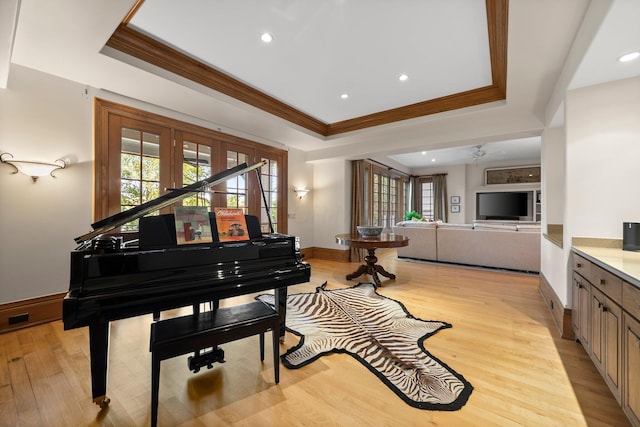 living area with a tray ceiling, ornamental molding, baseboards, light wood finished floors, and recessed lighting