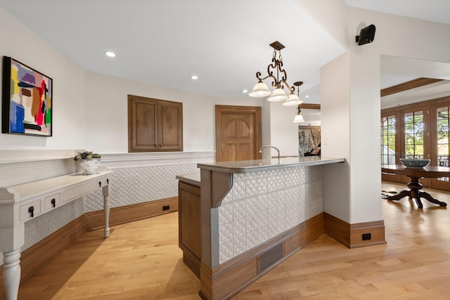 bar area with light wood-style floors, recessed lighting, decorative light fixtures, and a wainscoted wall