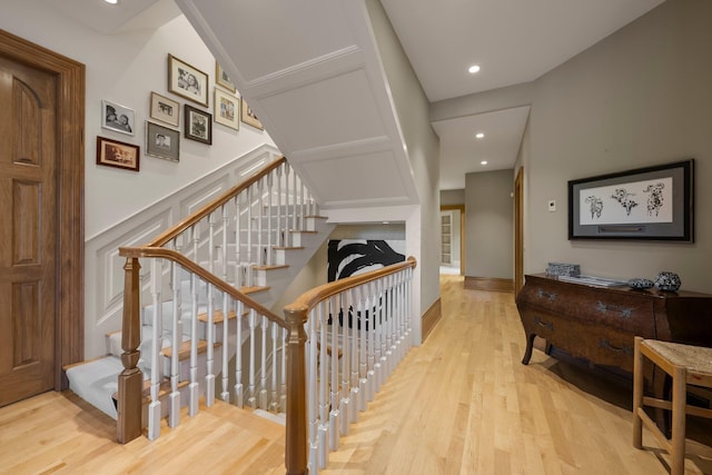 stairs featuring wood finished floors and recessed lighting