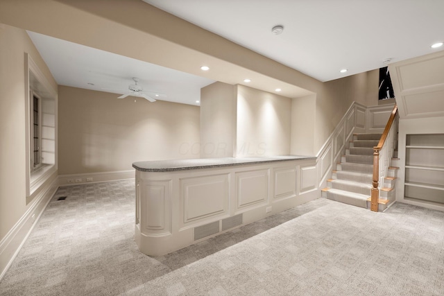 basement featuring light colored carpet, recessed lighting, ceiling fan, built in features, and stairway