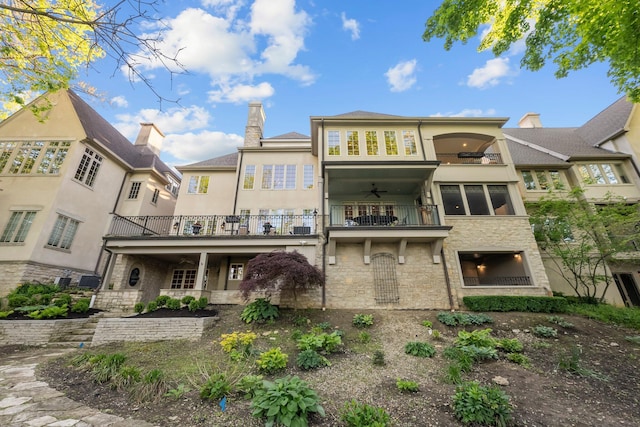 rear view of property featuring a balcony, stone siding, stucco siding, and a ceiling fan