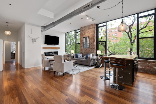 78 E Chestnut St Unit 205, Columbus, OH 43215 - living room featuring wood finished floors, brick wall, rail lighting, and baseboards