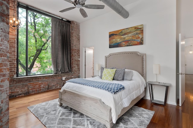 78 E Chestnut St Unit 205, Columbus, OH 43215 - bedroom with wood finished floors, brick wall, a ceiling fan, and baseboards