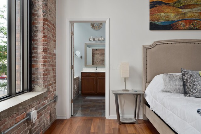 78 E Chestnut St Unit 205, Columbus, OH 43215 - bedroom with wood finished floors, connected bathroom, a sink, and baseboards
