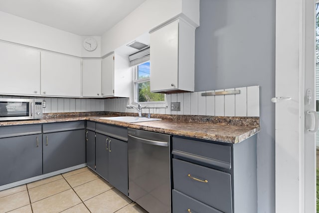 3204 Mcguffey Rd, Columbus, OH 43224 - kitchen featuring stainless steel appliances, dark countertops, a sink, light tile patterned floors, and white cabinetry