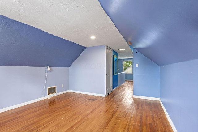 3204 Mcguffey Rd, Columbus, OH 43224 - bonus room with baseboards, a textured ceiling, hardwood / wood-style floors, and lofted ceiling